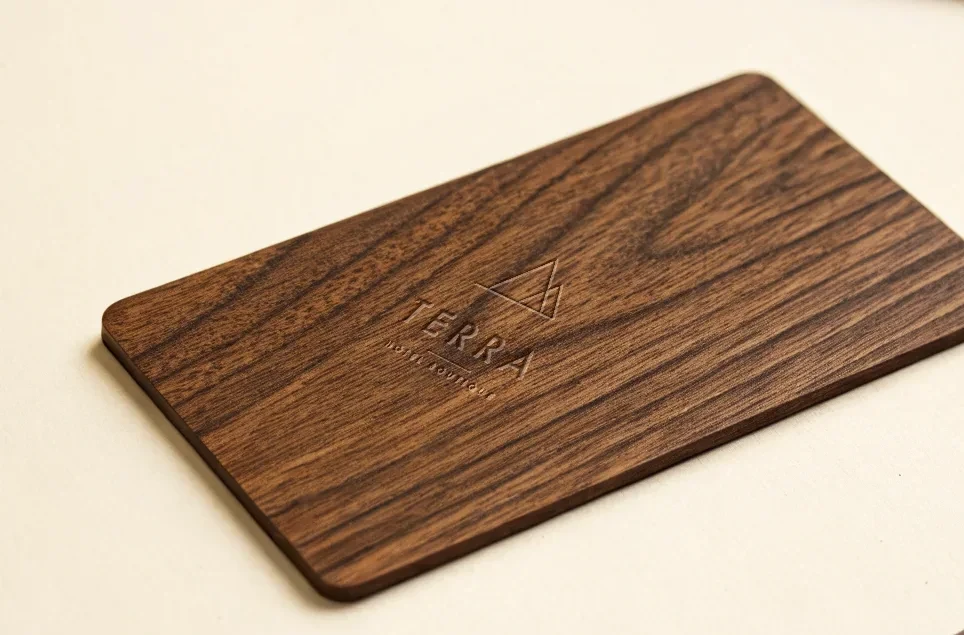 tarjeta de madera de nogal oscuro grabada a láser con el nombre Terra Hotel Boutique y una marca triangular fina