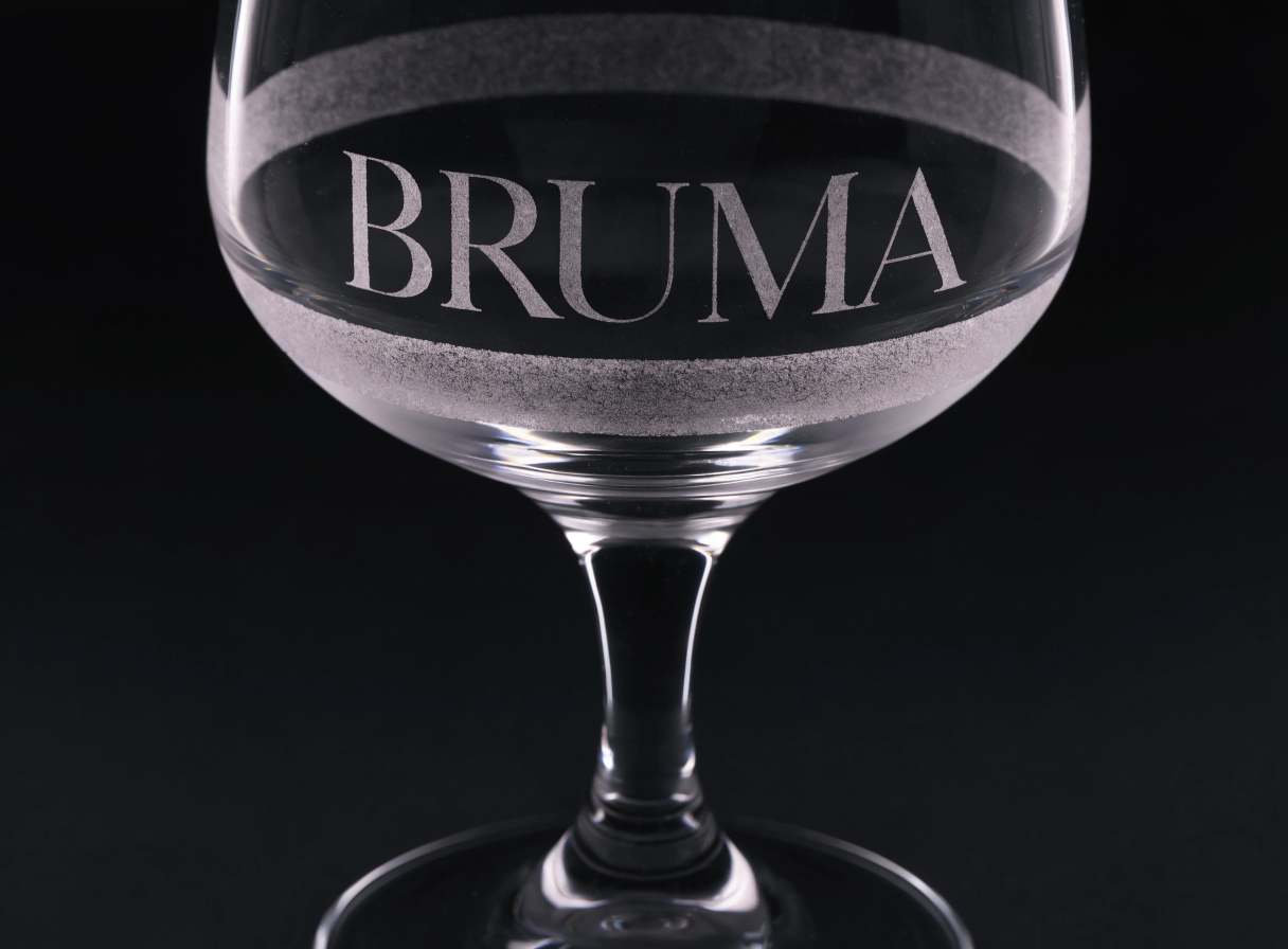 Copa de cristal de tallo con una banda arenada que rodea el cuenco y el nombre BRUMA reservado en cristal transparente dentro de la banda.