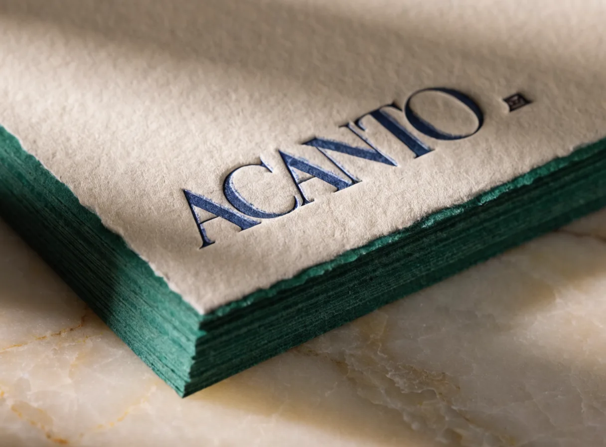 Bloque de tarjetas de algodón con canto pintado verde botella y orilla deckle, con el nombre impreso en letterpress azul marino sobre mármol claro.