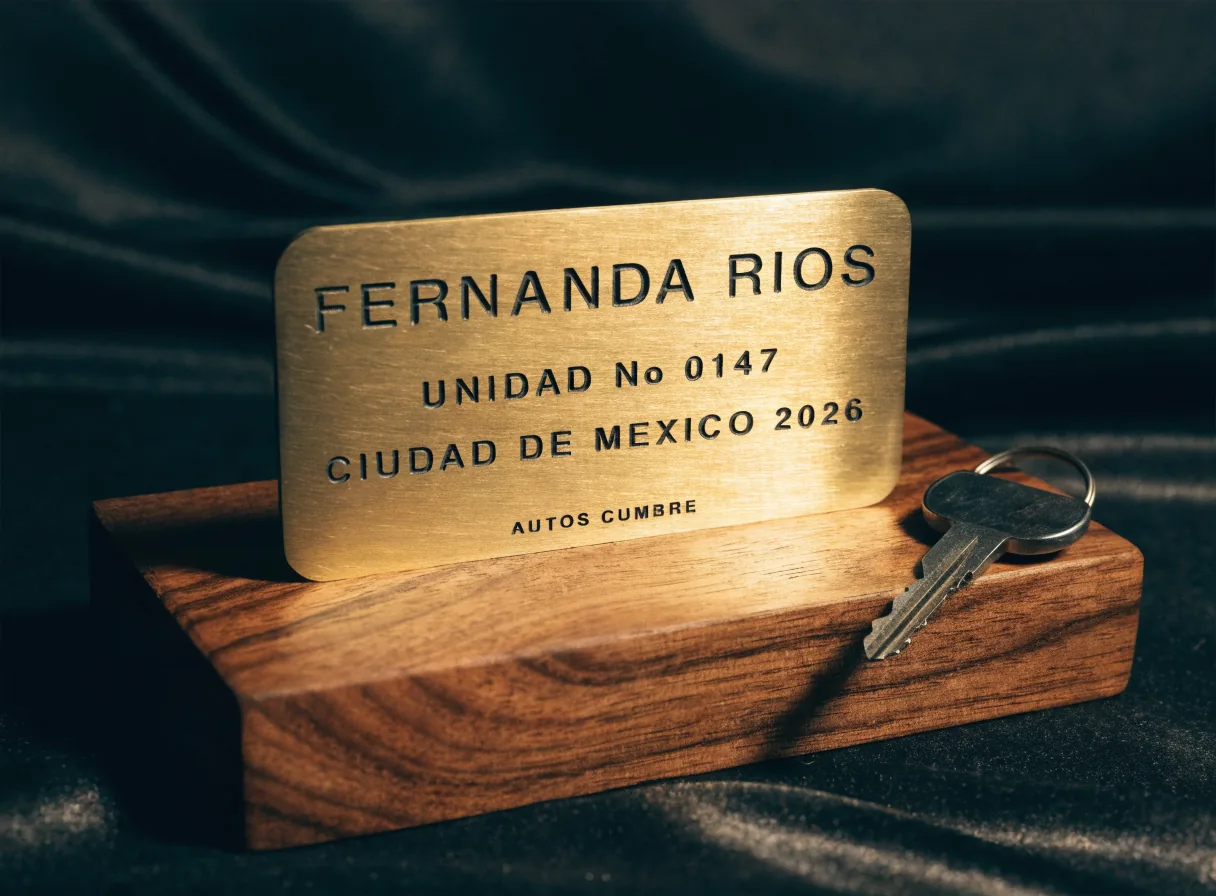 placa conmemorativa de entrega en latón sobre base de nogal, grabada con el nombre del dueño, la unidad número 0147 y el año 2026 para Autos Cumbre