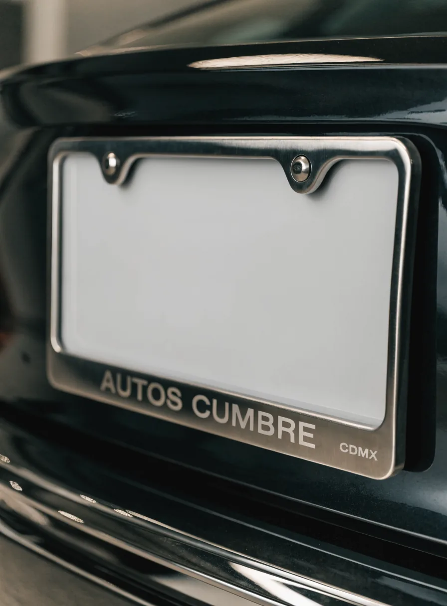 porta-placas de acero inoxidable en la parte trasera de un auto negro, grabado Autos Cumbre CDMX