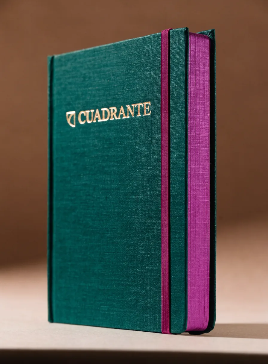 cuaderno de tapa dura entelada en verde profundo de la marca CUADRANTE con el canto de las hojas pintado en magenta a juego con el elástico y el nombre en foil dorado