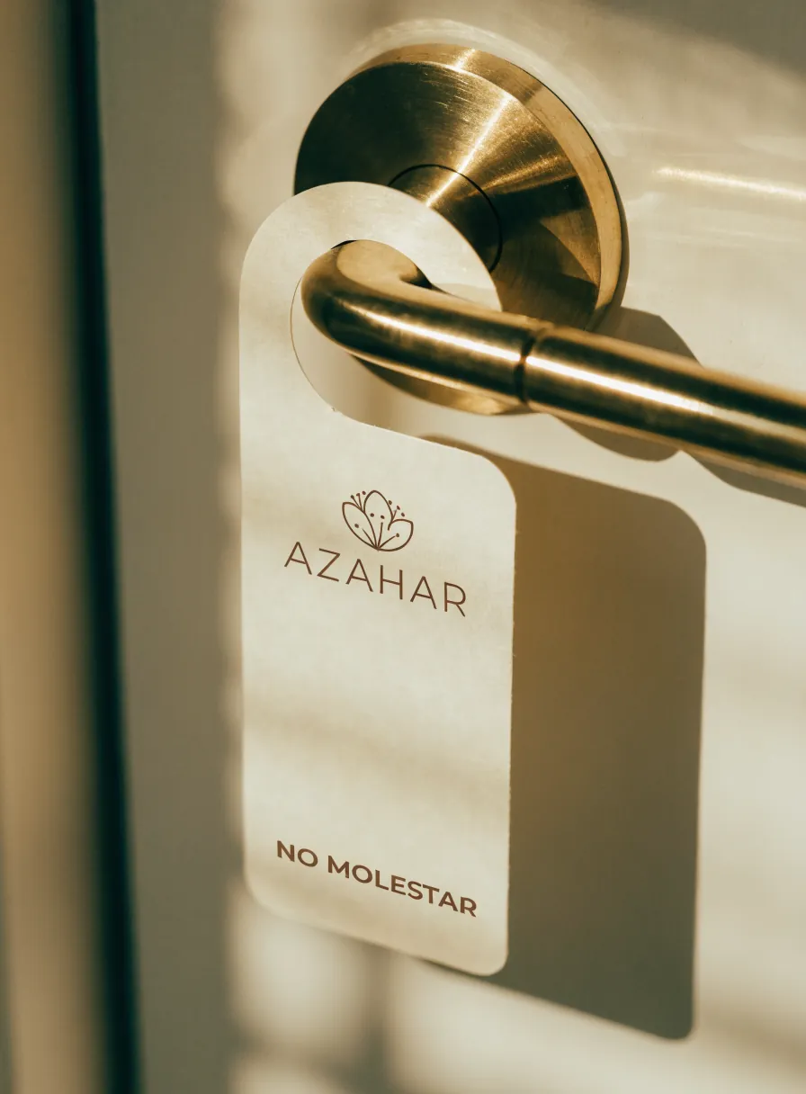 colgante de puerta color crema con la marca Azahar y la leyenda No molestar, en la manija de latón de una habitación