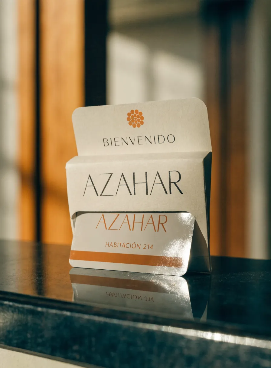 porta-tarjeta de bienvenida con una tarjeta-llave de habitación de la marca Azahar, sobre una barra de piedra oscura