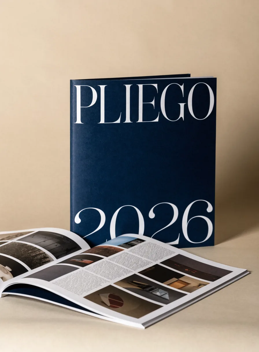 catálogo editorial de la marca ficticia PLIEGO con PLIEGO 2026 en tipografía blanca sobre azul marino, junto a una revista abierta con fotografías y columnas de texto