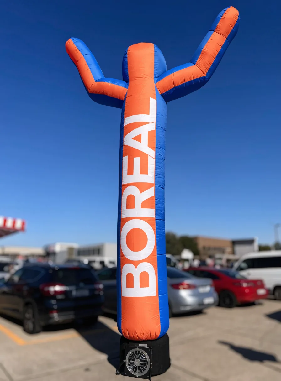 inflable tipo air dancer en naranja y azul con la marca BOREAL, agitándose sobre un estacionamiento bajo cielo despejado