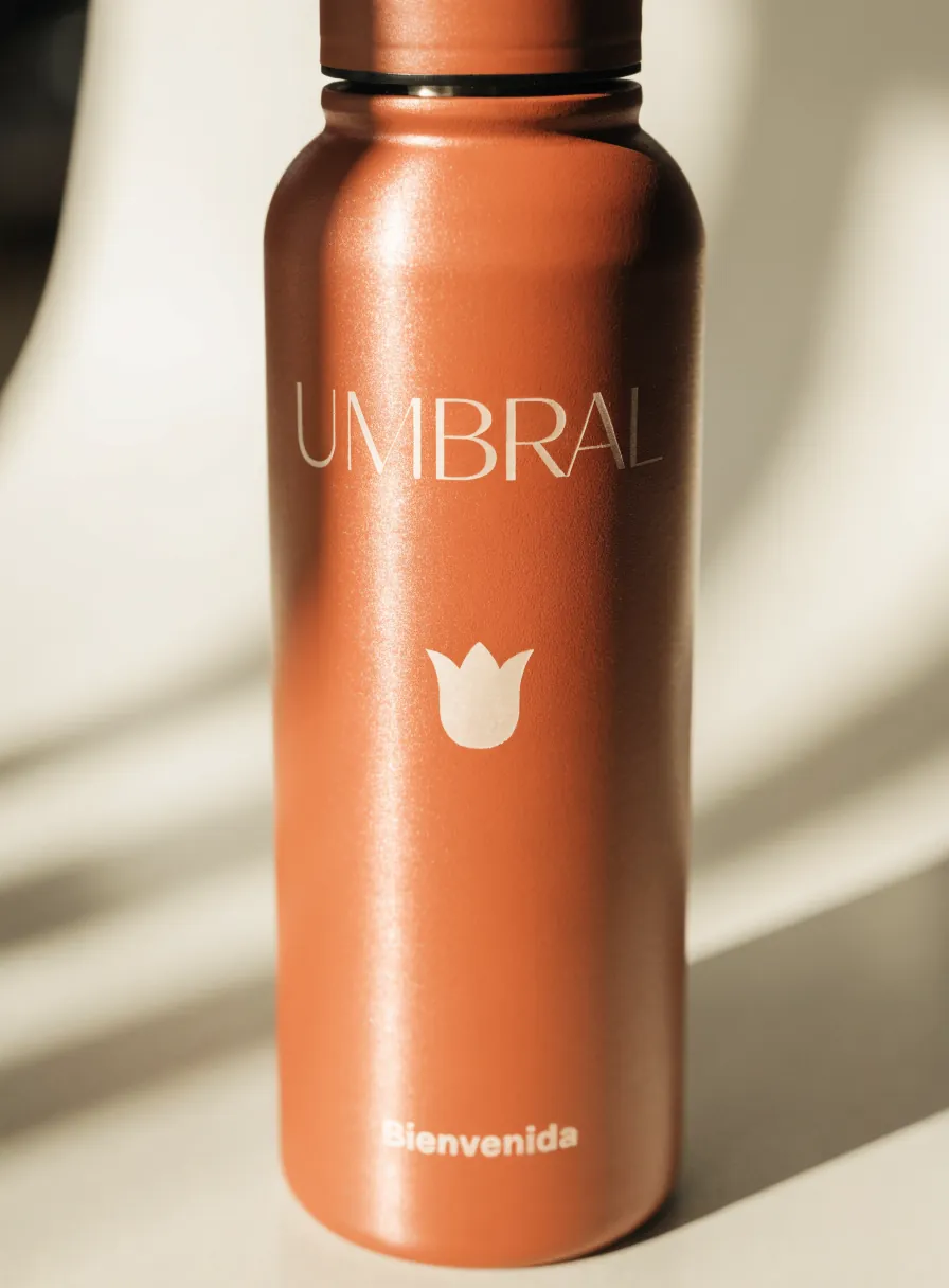 botella térmica de acero color terracota con el logotipo UMBRAL y la palabra Bienvenida grabados al frente
