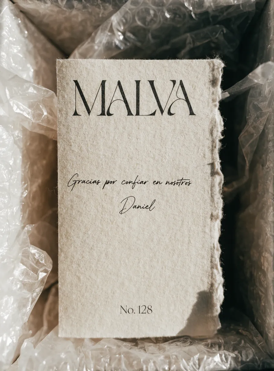 tarjeta de papel de barba color crema dentro de una caja, con la marca MALVA impresa y Gracias por confiar en nosotros firmada a mano por Daniel, No. 128
