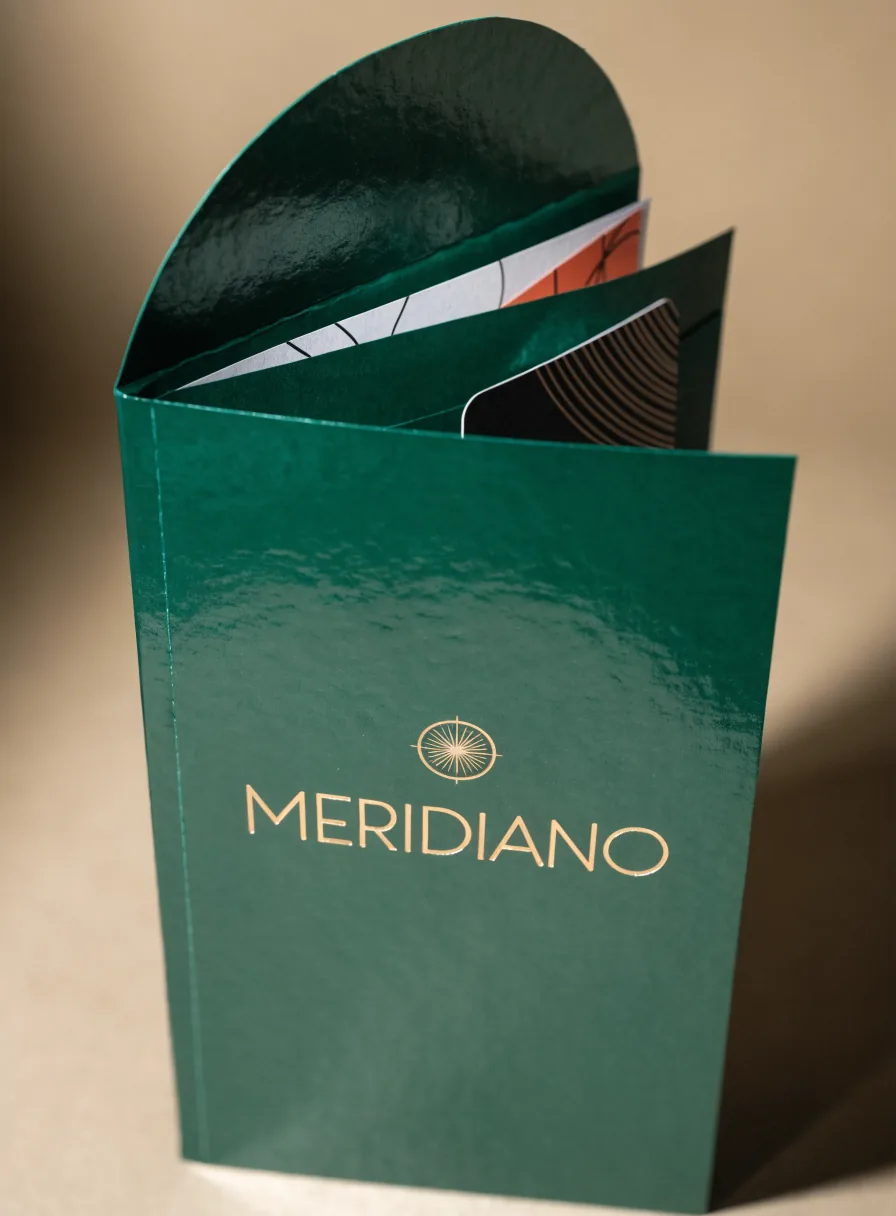 carpeta de presentación verde con el nombre Meridiano en foil dorado, abierta y con las hojas y la tarjeta del expediente adentro