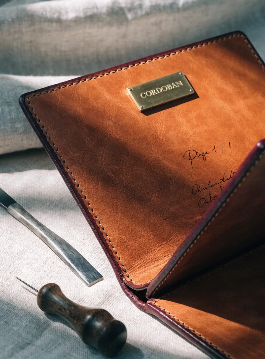 Portafolio de piel cognac cosido a mano y abierto, con una placa de latón grabada CORDOBAN y una nota manuscrita