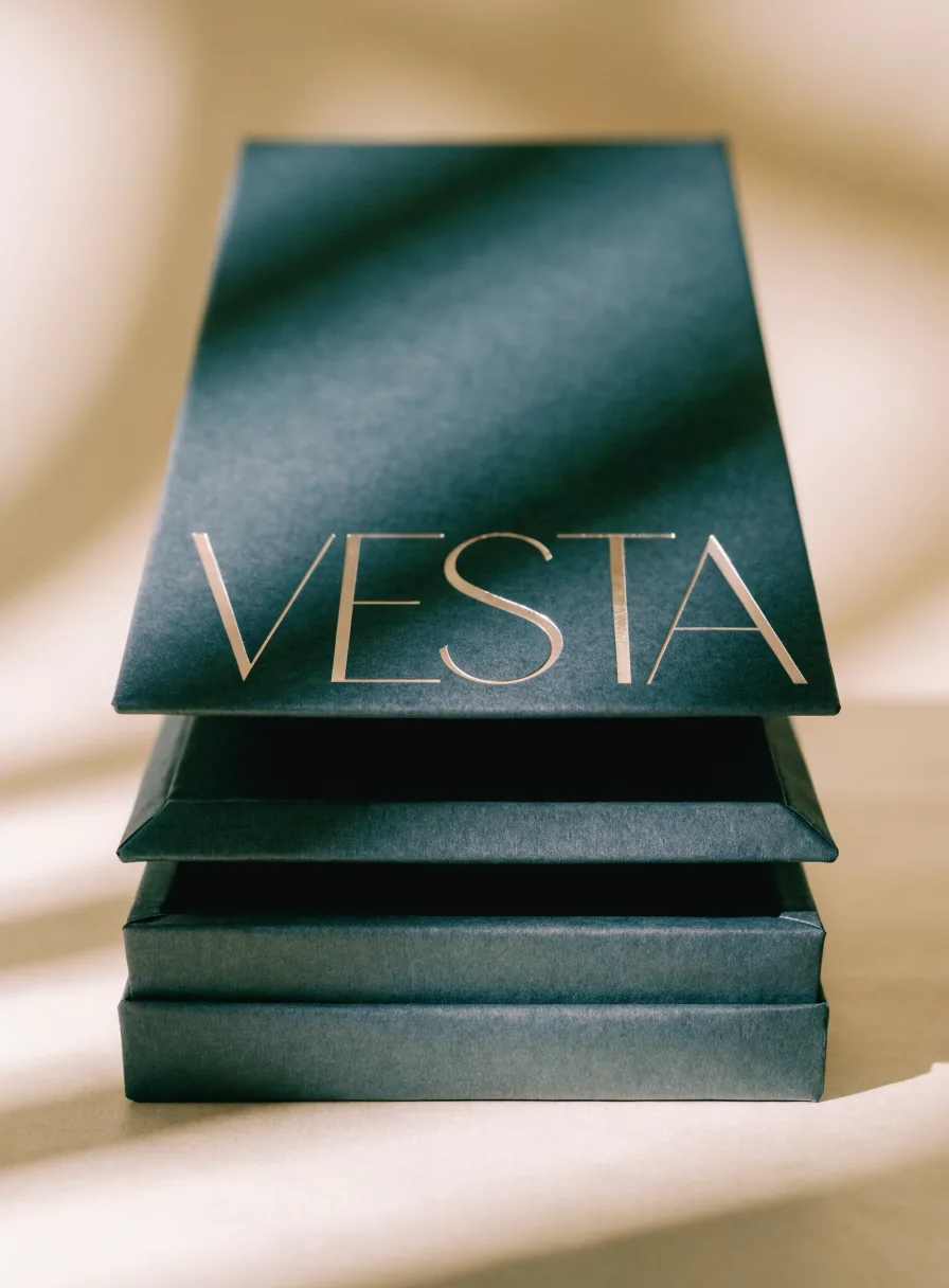 estuche telescópico de tres piezas en verde teal apiladas, con la palabra Vesta en foil oro sobre la tapa superior