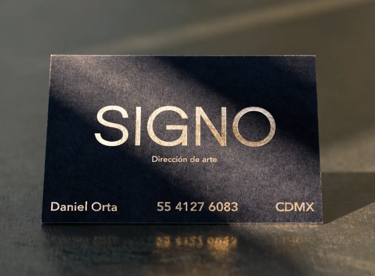 una tarjeta de la marca ficticia SIGNO en papel azul marino con laminado soft touch mate y el nombre en foil dorado