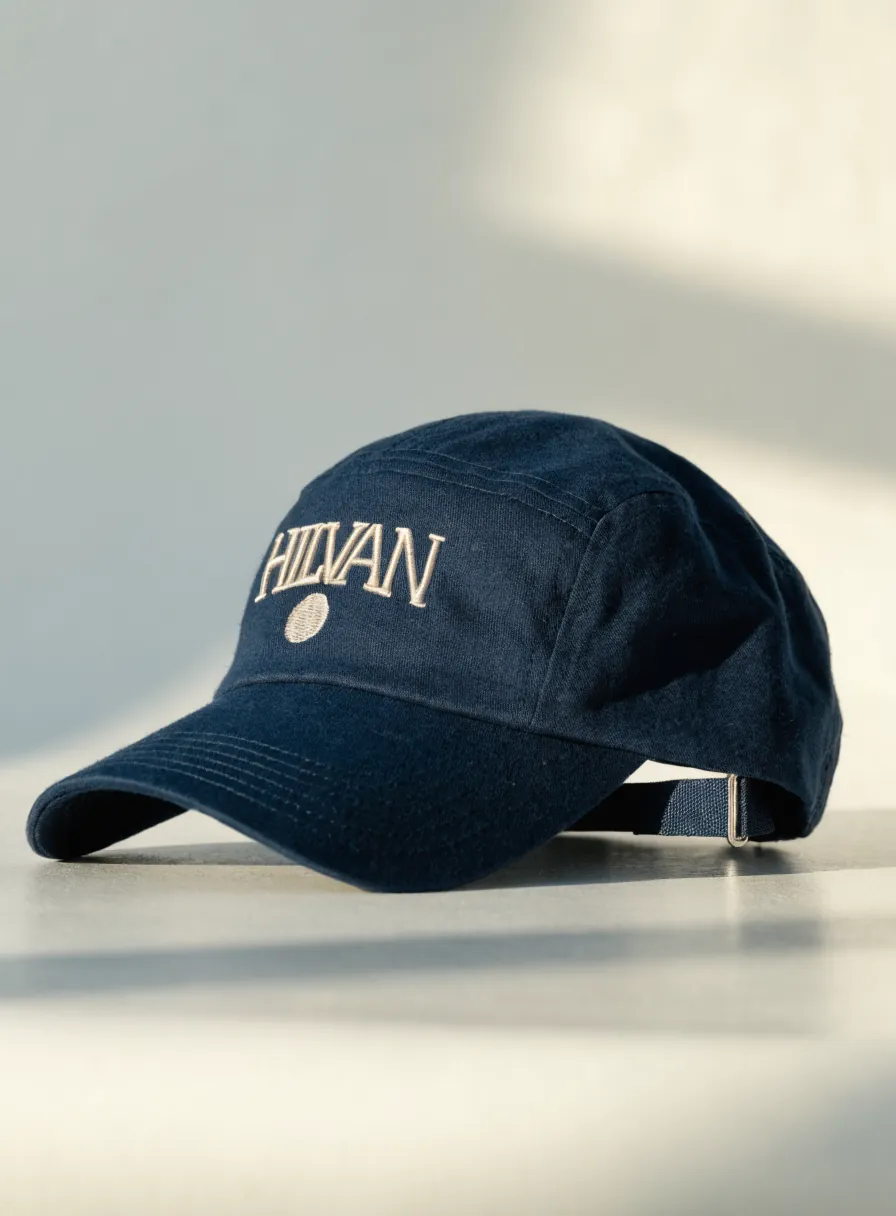 gorra de algodón azul marino con la palabra HILVAN bordada en hilo crema al frente y broche ajustable atrás