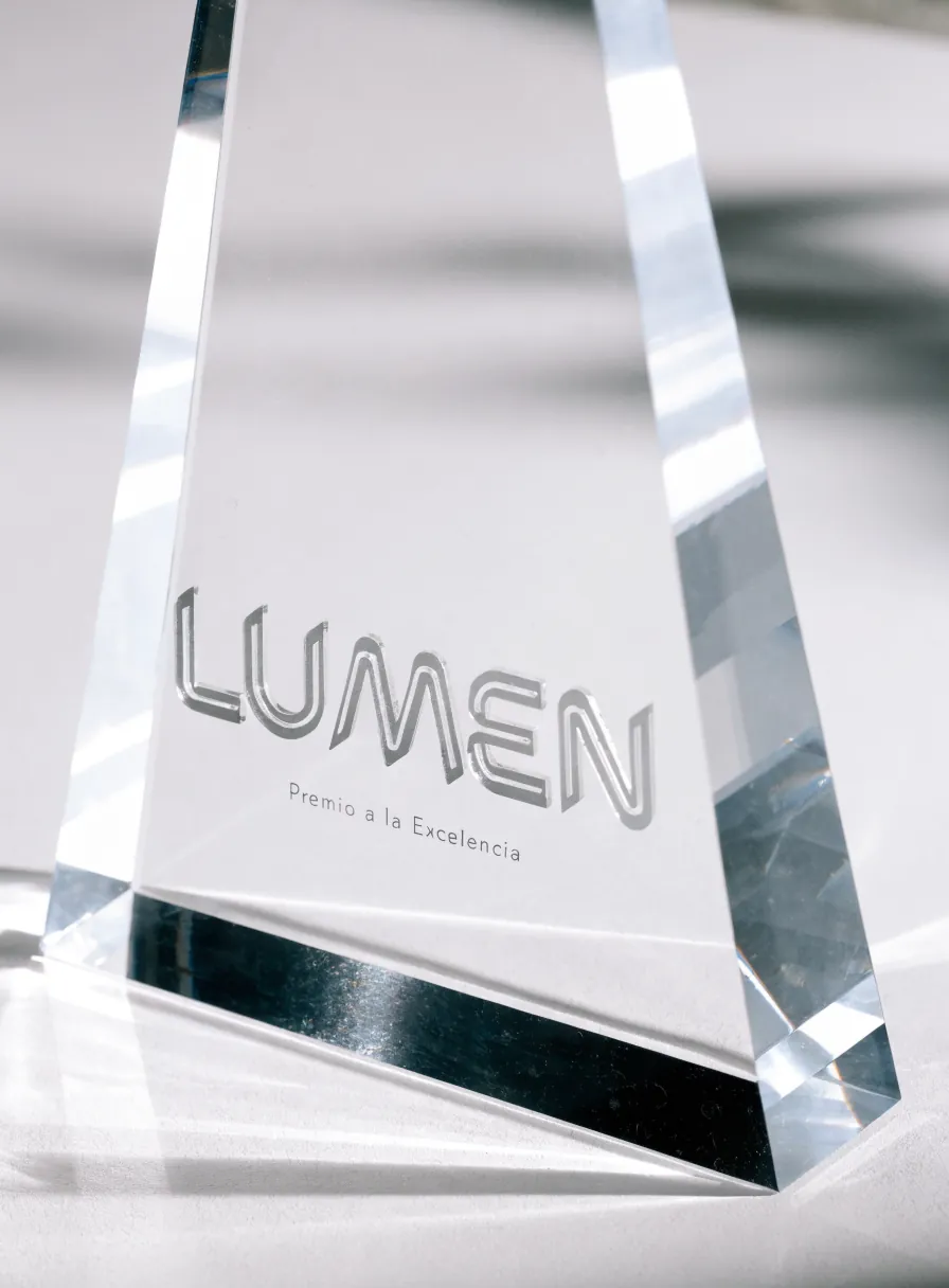 obelisco de cristal de canto grueso con la palabra Lumen y la línea Premio a la Excelencia trabajadas en relieve pulido