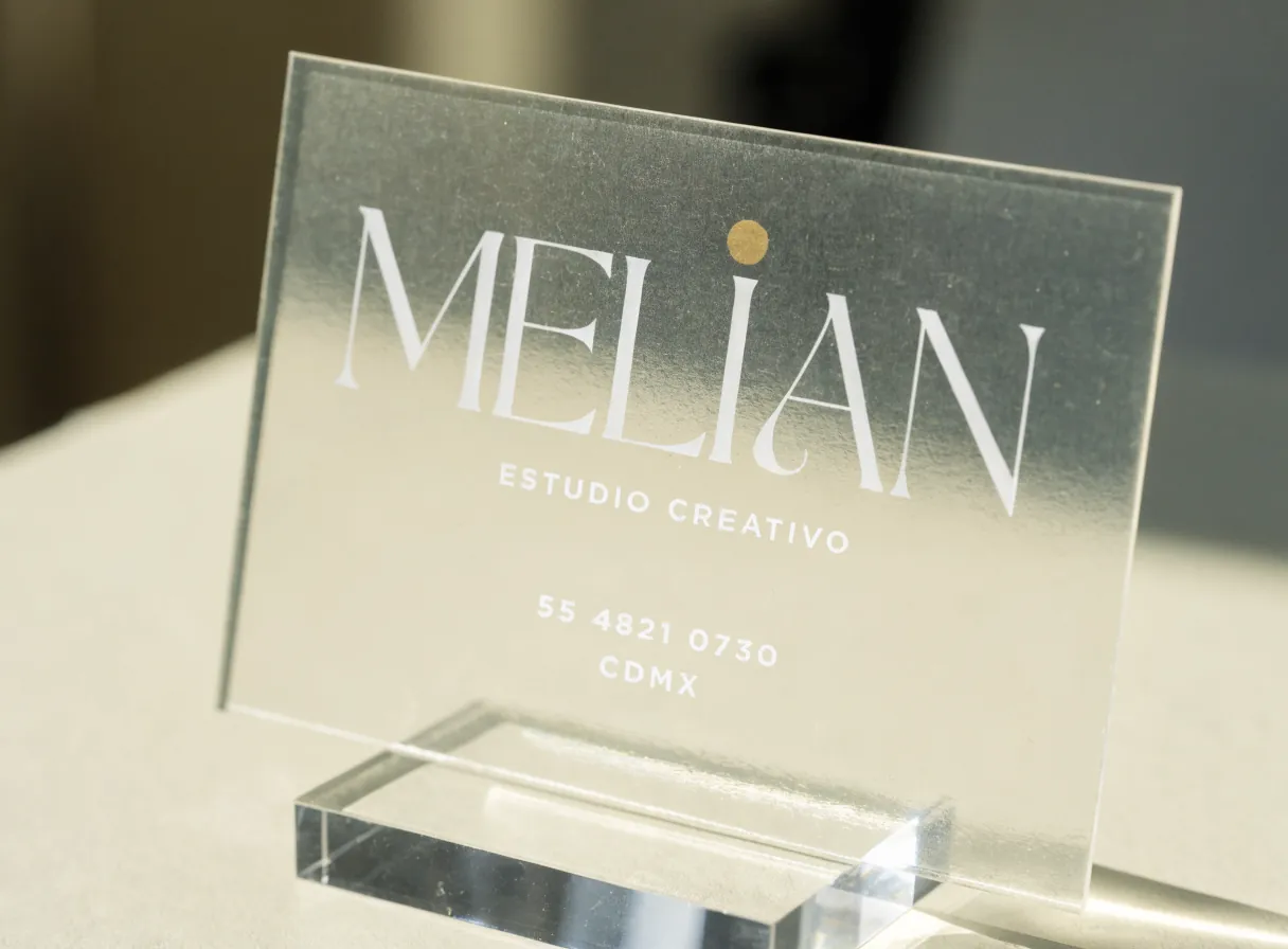 tarjeta de presentación transparente en acrílico esmerilado sobre un soporte de acrílico, con la marca ficticia Melián en blanco y un punto dorado, Estudio Creativo, CDMX