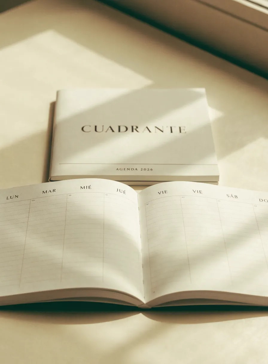 agenda de tapa blanda kraft cosida, abierta plana sobre una mesa clara con la marca en la portada