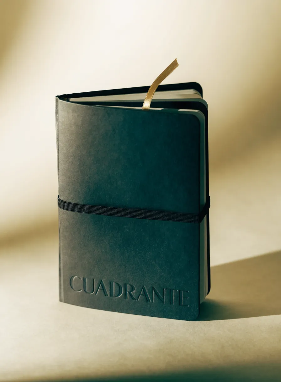 libreta de tapa suave al tacto en verde profundo de la marca Cuadrante, con el nombre en bajorrelieve, un elástico negro de cierre y un separador dorado