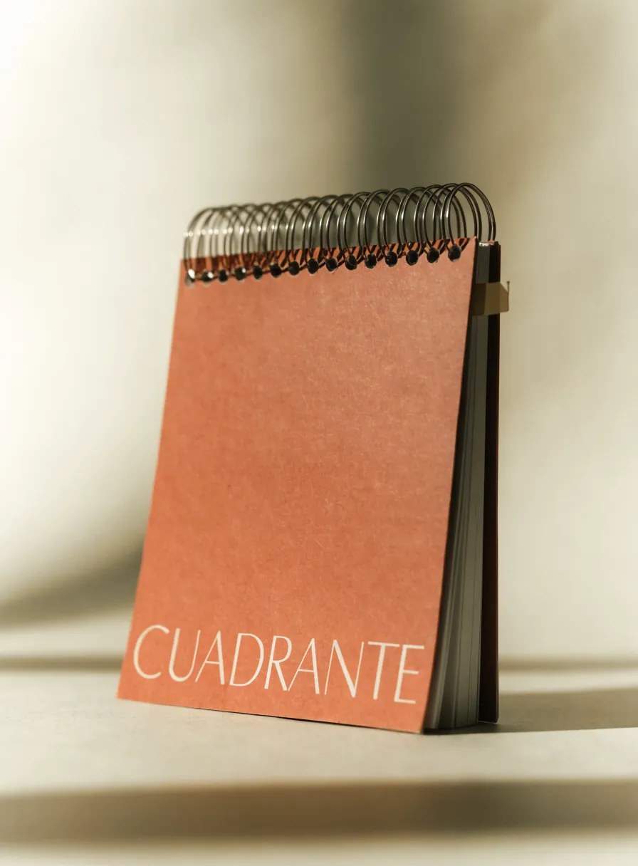 Cuaderno de tapa kraft terracota con arillo metálico doble de pie sobre la mesa