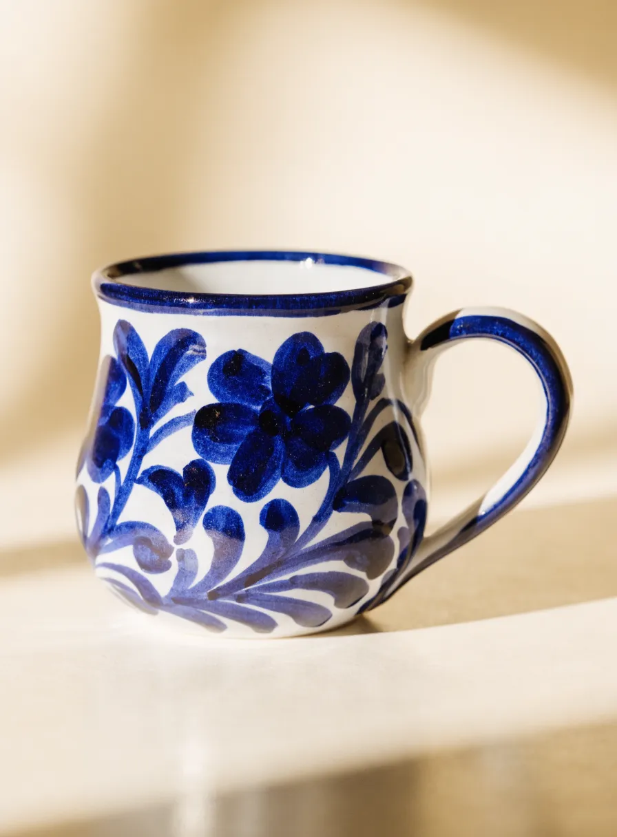 Taza de cerámica blanca con un motivo floral pintado a mano en azul