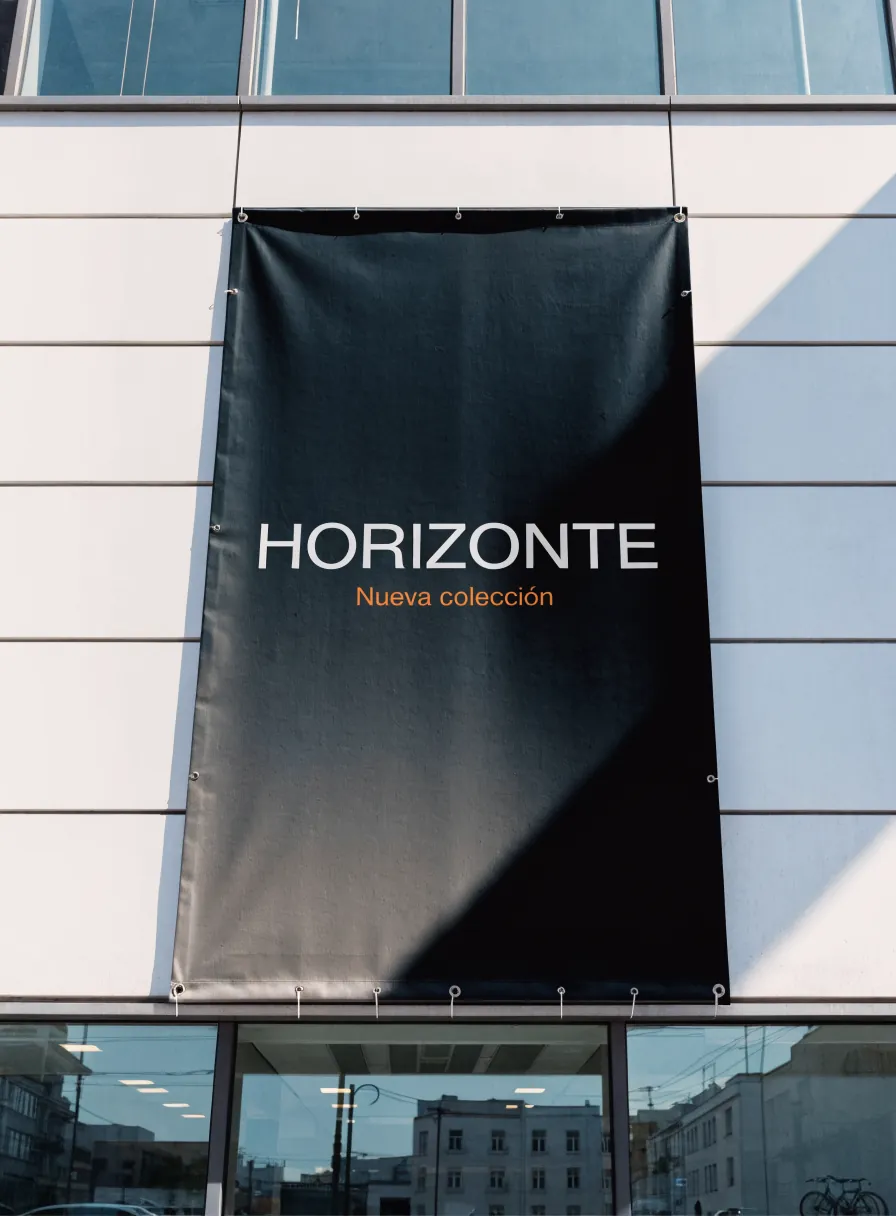 lona vertical negra con ojales colgada en la fachada de cristal de un edificio, que anuncia Horizonte, nueva colección