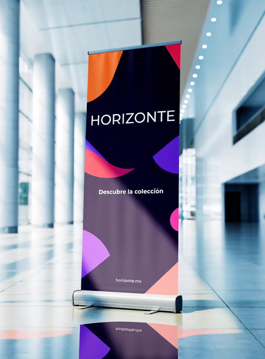 rollup retráctil con la marca Horizonte y formas de color sobre fondo oscuro, de pie en el pasillo de un centro de convenciones