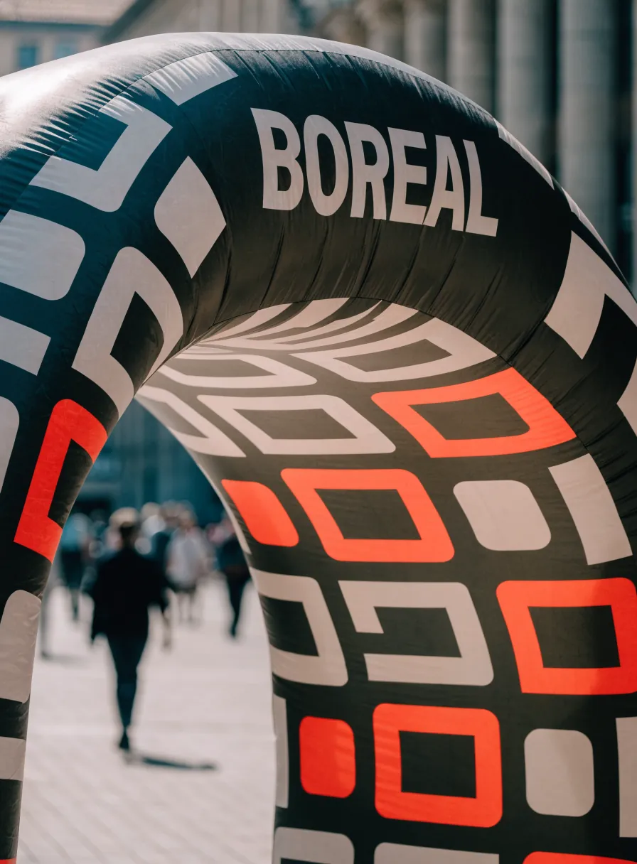 arco inflable estampado con tu marca en un patrón geométrico de crema y naranja sobre azul marino, montado en una calle