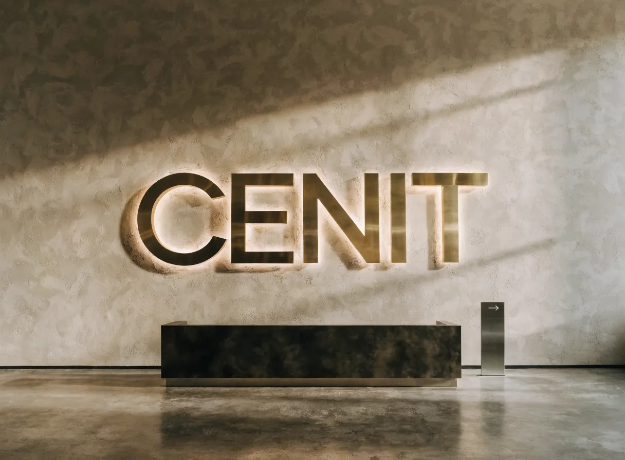 letras corpóreas de latón CENIT retroiluminadas en el muro de una recepción, con tótem de señalética