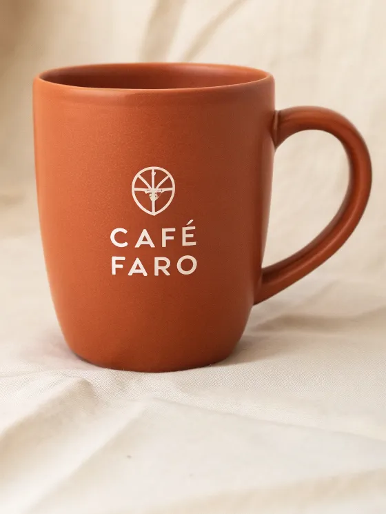 taza de cerámica terracota mate con el sello de un café de la marca ficticia Café Faro en serigrafía