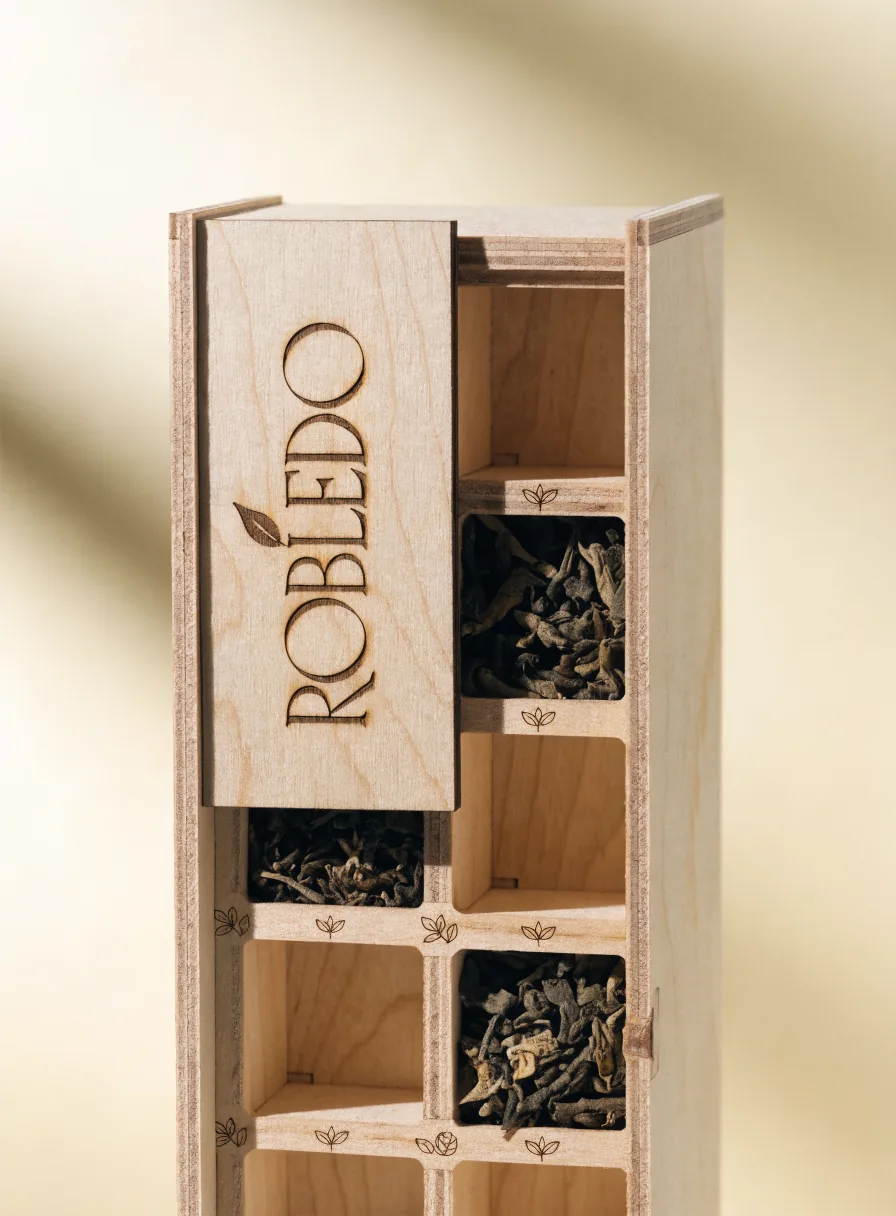 caja de contrachapado birch con tapa corrediza grabada ROBLEDO y una hoja, dividida en compartimentos con té a granel