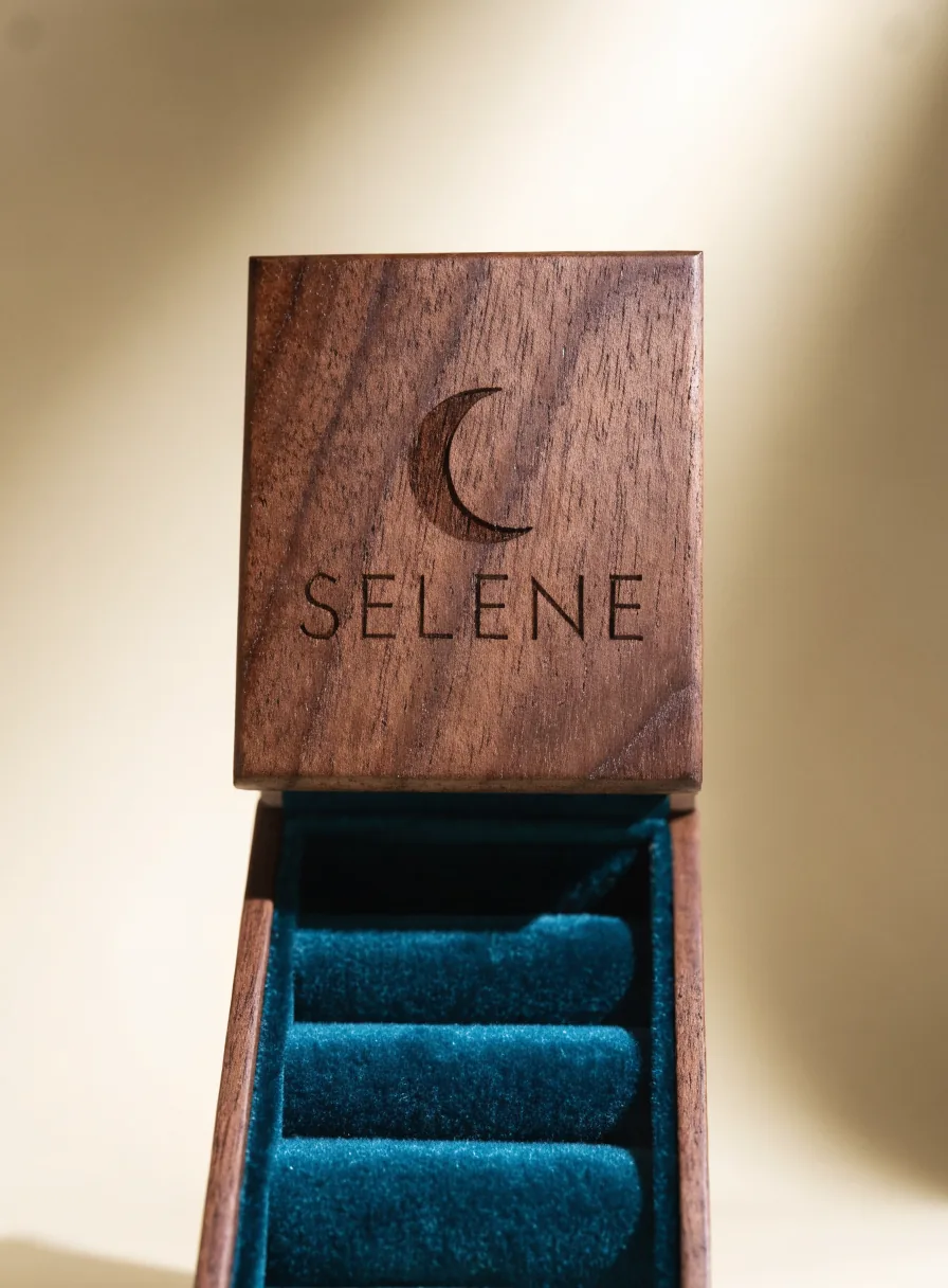 joyero de madera de nogal con una luna grabada a láser y el nombre de la marca, con interior de terciopelo azul
