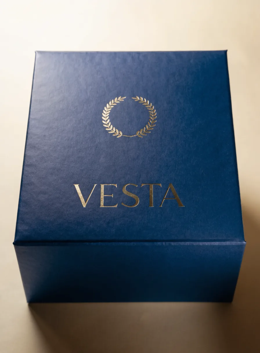 estuche de tapa dura azul noche con una insignia de laurel y la palabra Vesta en foil oro