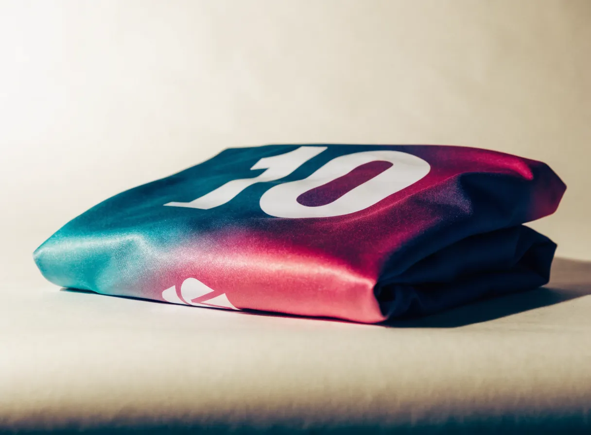 jersey deportivo con el número diez sublimado a todo lo ancho en magenta, azul y teal, doblado