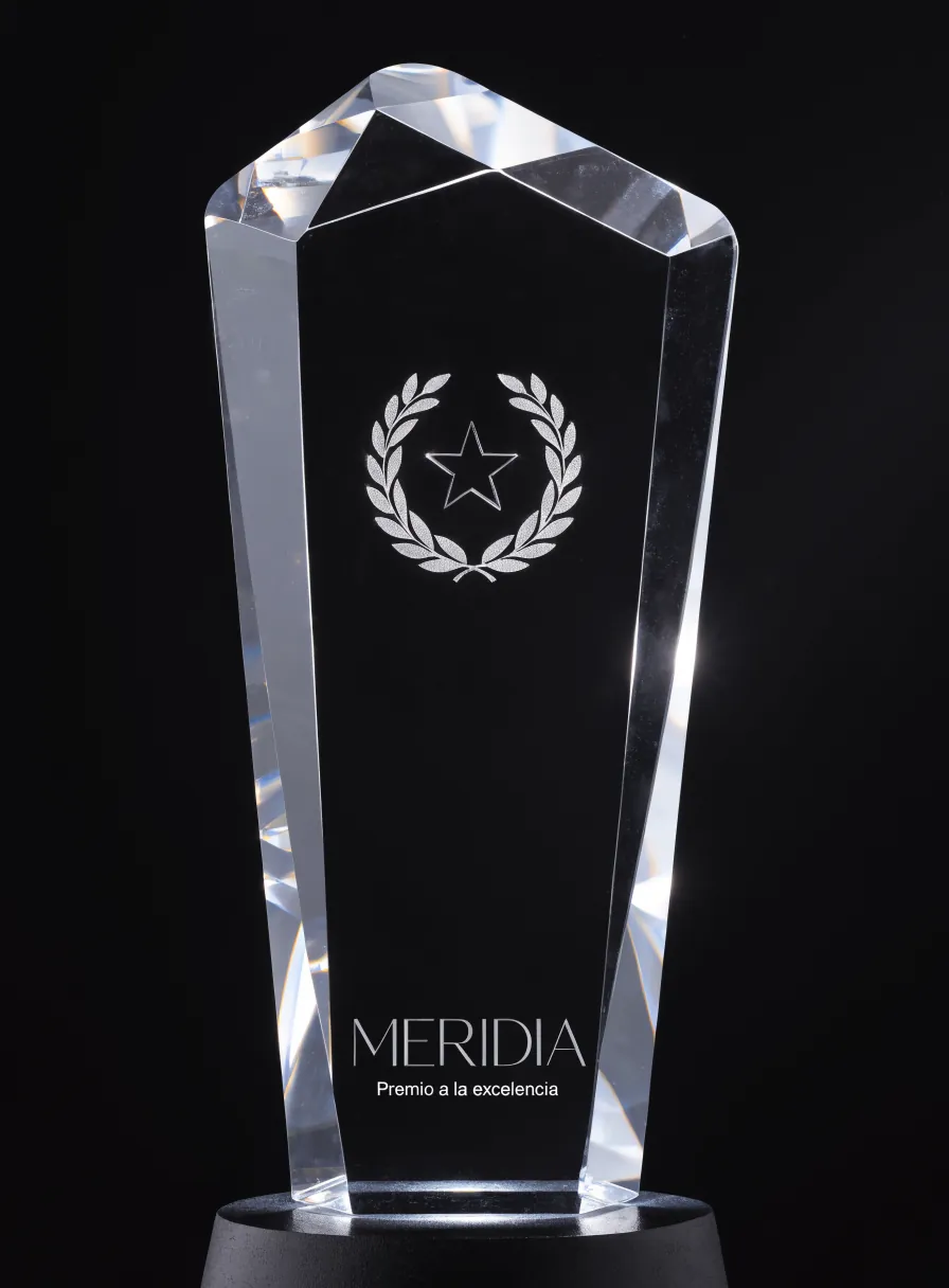 premio de cristal óptico K9 con un laurel y una estrella grabados en 3D dentro del bloque y la marca MERIDIA al frente, sobre una base iluminada
