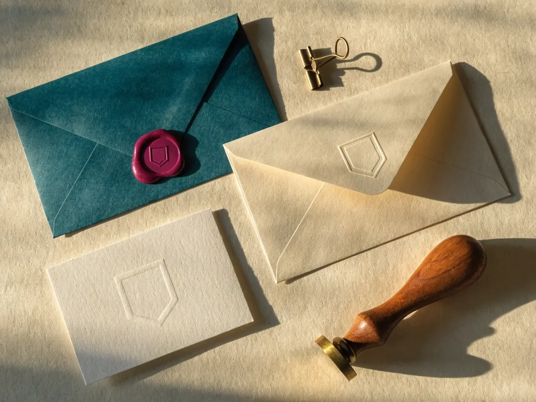 juego de papelería con sobres crema y teal, tarjeta con relieve ciego y sello de lacre sobre papel crema