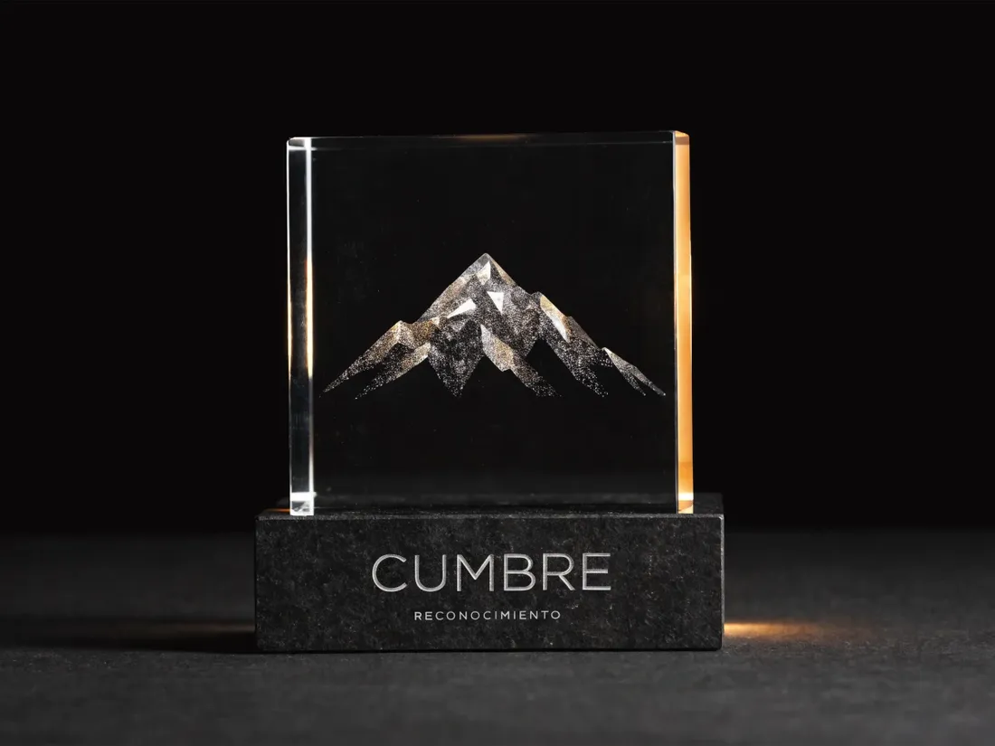 reconocimiento de cristal con un pico de montaña grabado en el interior, sobre base de piedra, con la marca Cumbre