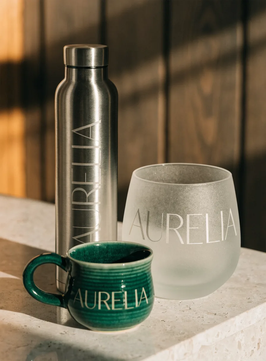 Botella de acero grabada AURELIA, vaso de cristal arenado y taza de gres verde con la misma marca