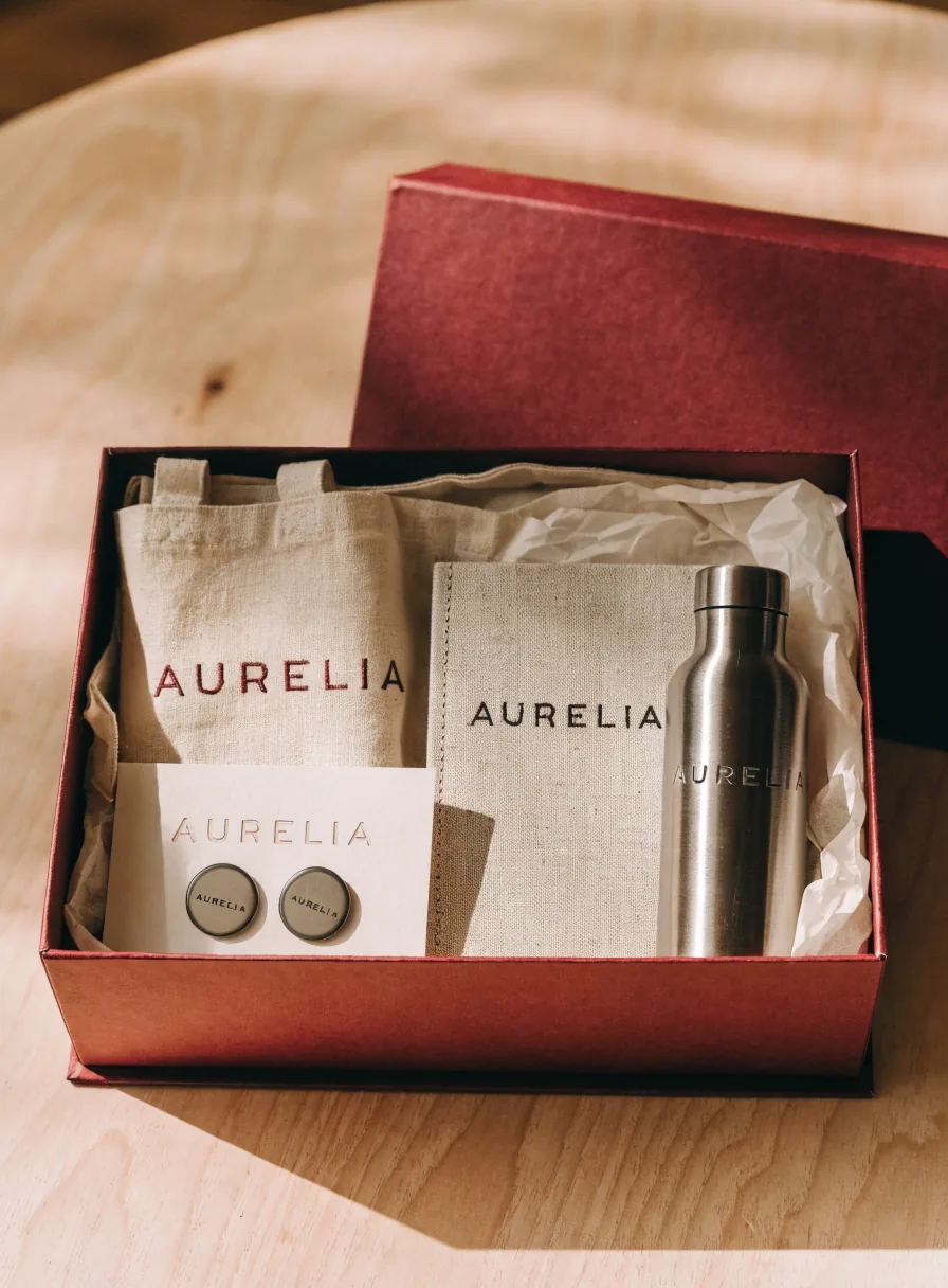 Caja rígida vino abierta con tote de lona, libreta de lino y botella de acero, todo con la marca AURELIA