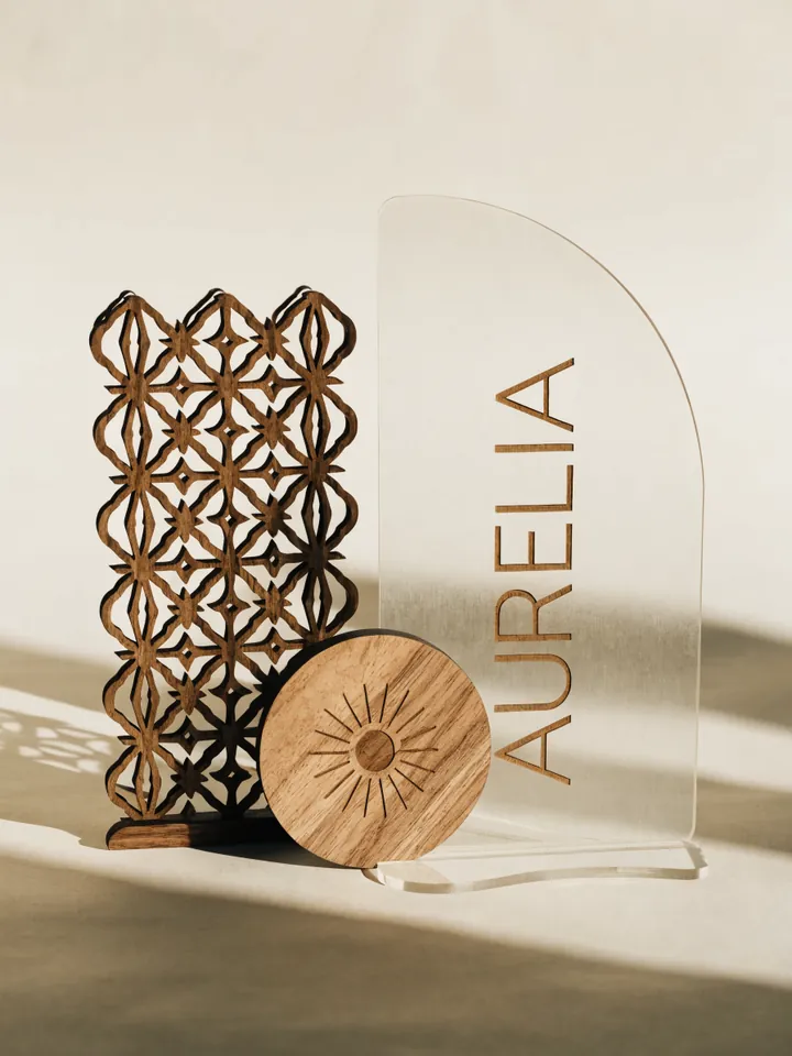letras de acrílico curvo con la marca AURELIA junto a un panel de celosía de madera y un disco grabado