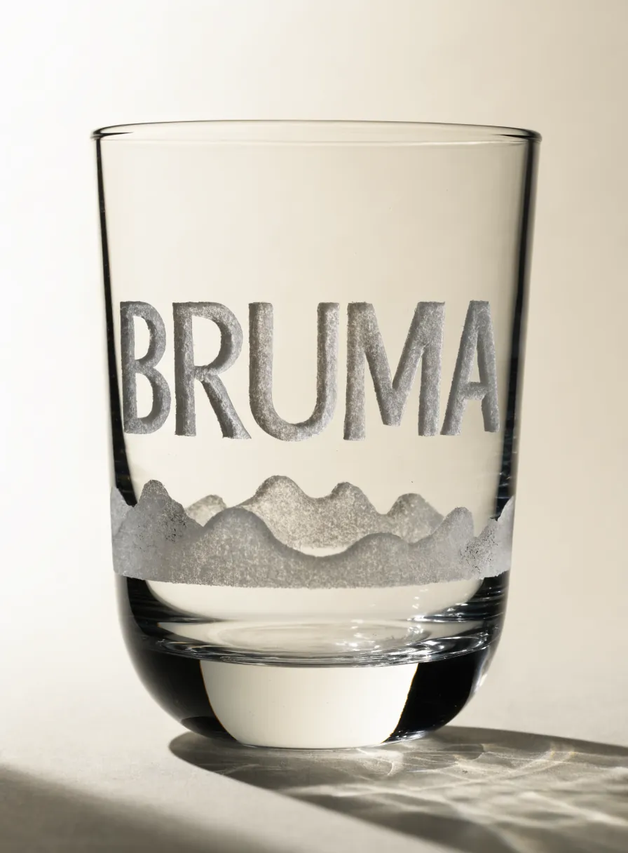 vaso de vidrio arenado con la palabra Bruma y una silueta de montañas en acabado esmerilado mate, a contraluz