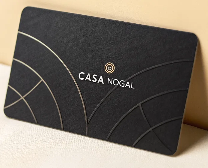 tarjeta negra de la marca ficticia Casa Nogal con líneas curvas en barniz UV y emblema circular en cobre