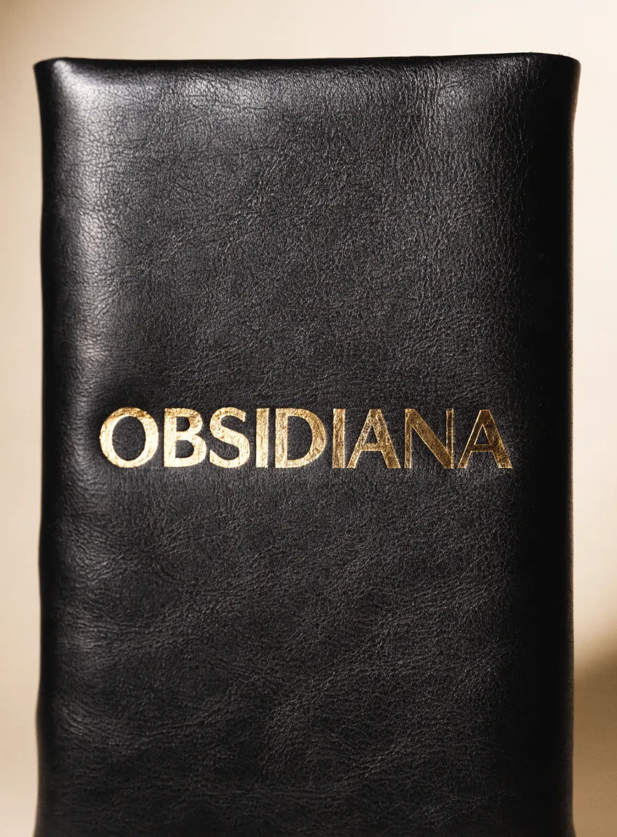 pieza de piel negra con la palabra OBSIDIANA sellada al calor en foil de oro espejo