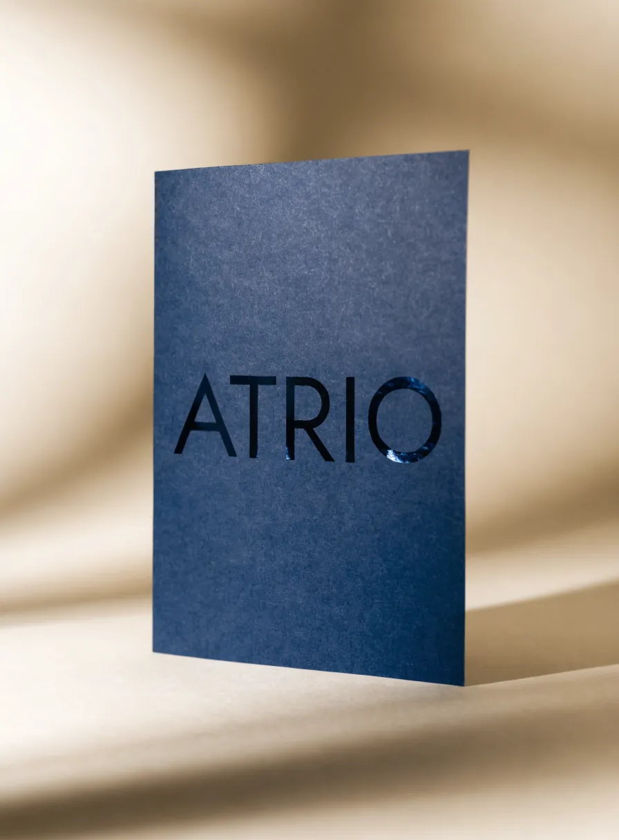 tarjeta azul marino mate con la palabra ATRIO en barniz UV brillante tono sobre tono que atrapa la luz