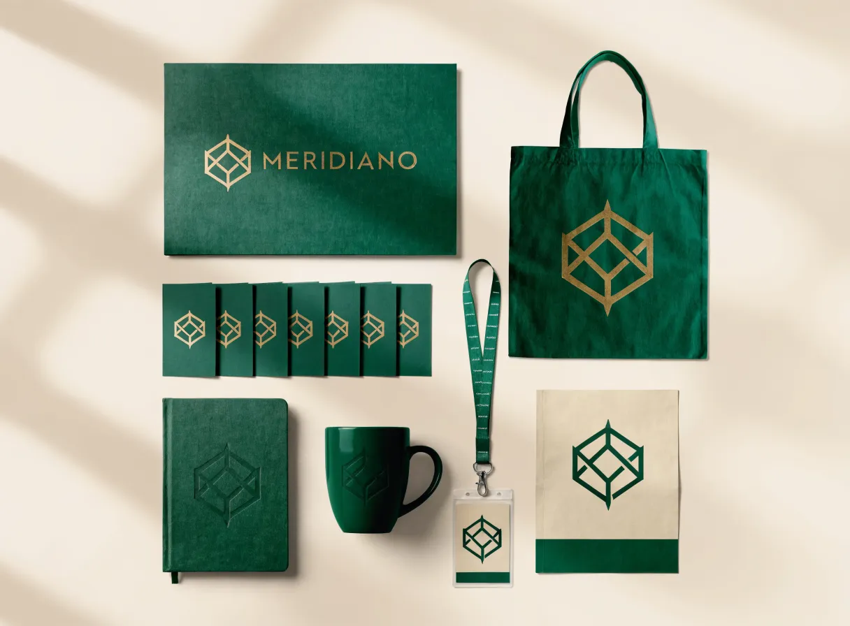 abanico de tarjetas verde bosque de la marca ficticia Meridiano con foil dorado, junto a folder, libreta y tote a juego sobre fondo crema