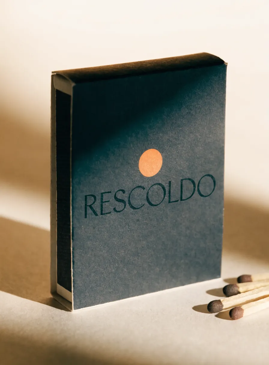 caja de cerillos impresa en azul noche con punto de cobre y cerillos de cabeza oscura al lado