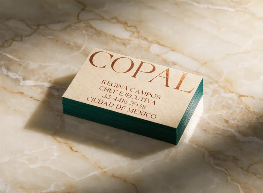 tarjetas de presentación en papel algodón con foil cobre y canto verde sobre superficie de ónix